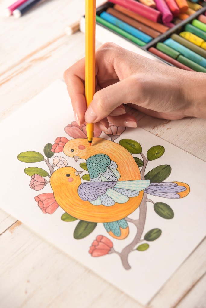 Hand coloring a printed worksheet with markers and pastels
