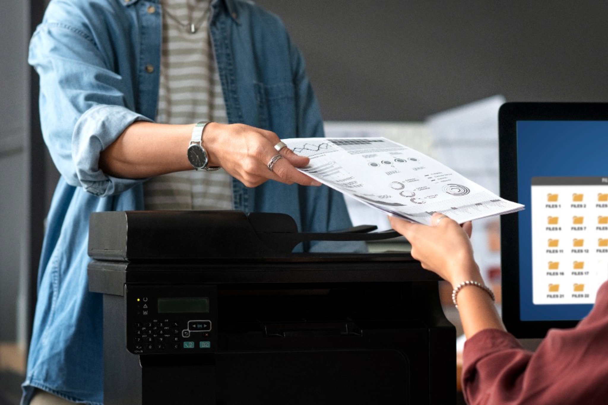 Staff handing printed documents to a customer at the print counter